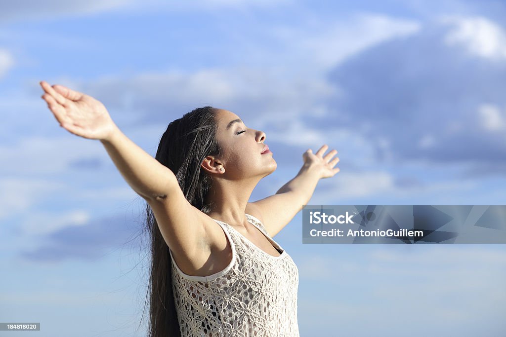 Beautiful arab woman breathing fresh air with raised arms Beautiful arab woman breathing fresh air with raised arms with a cloudy blue sky in the background Adult Stock Photo