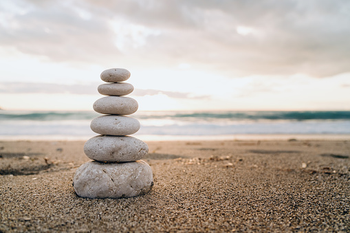 A cairn of smooth stones stacked on the sand symbolizes balance and tranquility by the sea