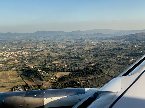 Window View of Passenger Jet Wing Flying Over the Tuscany Region of Northern Italy in the Late Afternoon About to Land