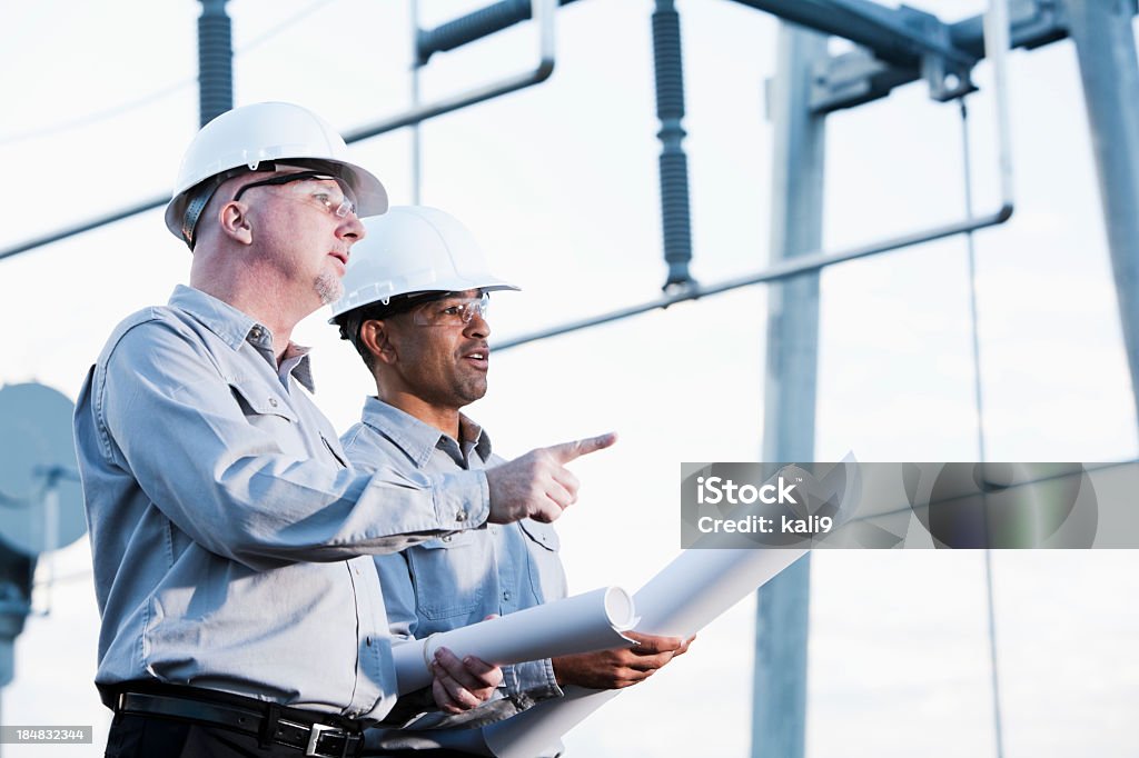 Multirracial los ingenieros industriales mirando hacia arriba en el sitio - Foto de stock de Ingeniero libre de derechos