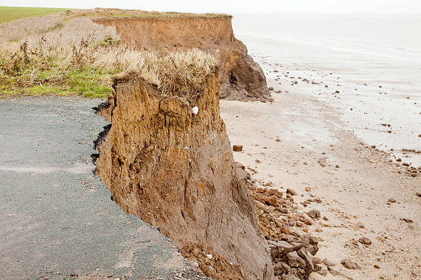 Close-up of a coastal road destroyed over time by erosion "Coastal erosion and the end of a road on the Holderness coastline of East Yorkshire, England.  This section of coast experiences some of the worst erosion in Britain, losing approximately 2 metres per year.Visit my Coast Lightbox for more images from around the British coast." eroded stock pictures, royalty-free photos & images