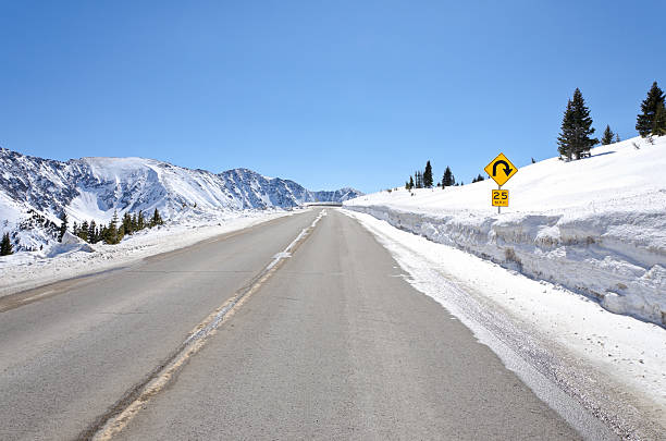 istock 25 MPH Curve Ahead Sign in Mountains Winter 184832494