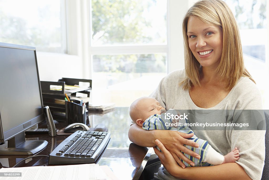 Mother working in home office with baby Mother working in home office with baby smiling at the camera 30-39 Years Stock Photo