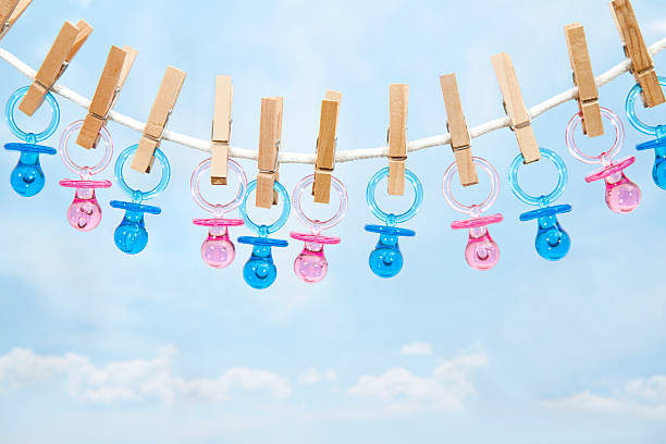 Pink And Blue Pacifiers Hanging On A Clothesline Pink And Blue Pacifiers Hanging On A Clothesline its a girl pacifier clothesline newborn stock pictures, royalty-free photos & images