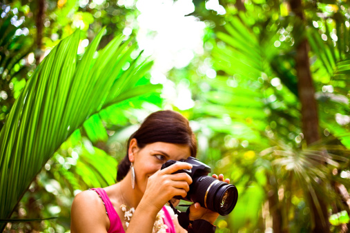 Beautiful woman taking picture on the tropical vacation, palm grove in the background.