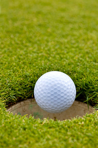 close-up of golf ball falling en orificio pasante - putting down fotografías e imágenes de stock
