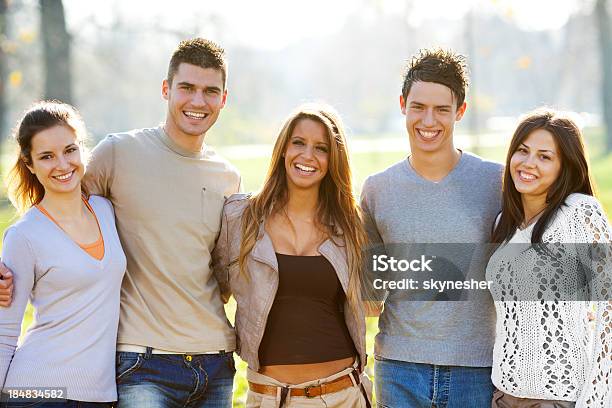 Hermoso Rodeado Amigos De Pie En El Parque Foto de stock y más banco de imágenes de Abrazar - Abrazar, Adolescencia, Adolescente