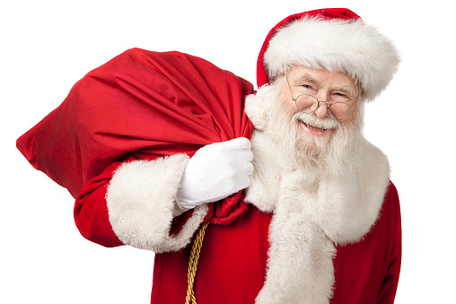 Waist up portrait of traditional Santa Claus holding sack with presents and smiling at camera in night city with lights, copy space