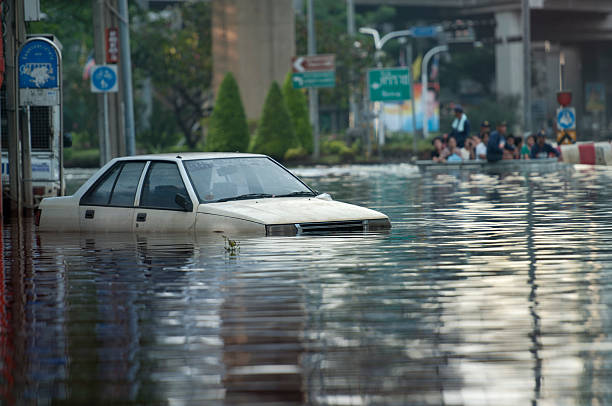 Flooded Car Flooded car with rescue boat full of people in the background flood stock pictures, royalty-free photos & images
