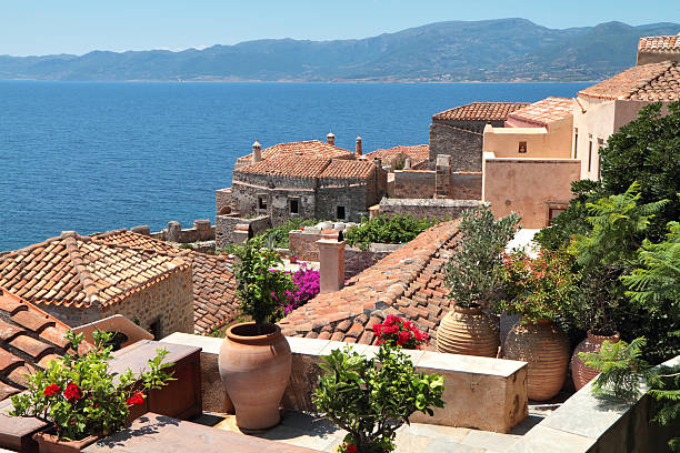 Red Tiled Rooftops of Monemvasia, Laconia Region, Peloponnese, Greece "The red tiled rooftops and narrow alleyways of the charming Byzantine town of Monemvasia.  The red tiles contrast with the deep blue of the Mediterranean Sea.  Located in the Laconia region of the Peloponnese, the town is attached to the mainland by a single thin causeway." monemvasia stock pictures, royalty-free photos & images