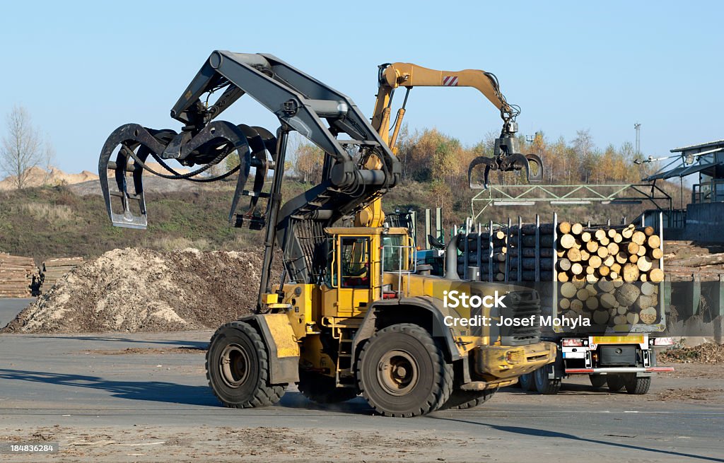 Unloading of Logging Truck Logging Truck is unloaded after arrival to saw mill. Wheel loader in action. Mechanical Grabber Stock Photo
