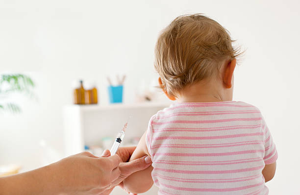 baby girl patient receiving vaccine at doctor's office - bebeklik stok fotoğraflar ve resimler