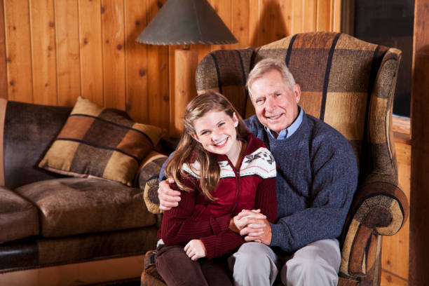 chica con abuelo en la sala de estar de la cabaña - coat grandfather grandchild granddaughter fotografías e imágenes de stock