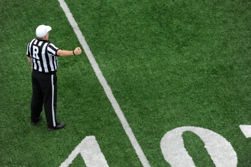 A football referee signals for play to start.