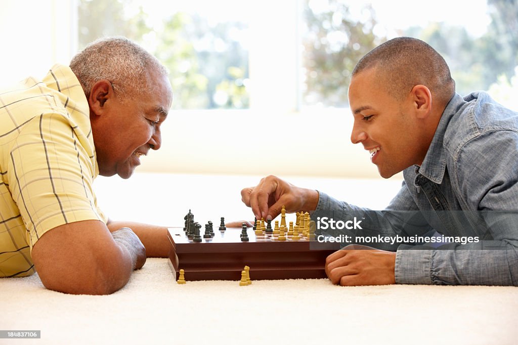 Senior man playing chess with son Senior man playing chess with son having fun Senior Adult Stock Photo