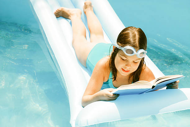 istock Girl reading in swmimming pool 184837600