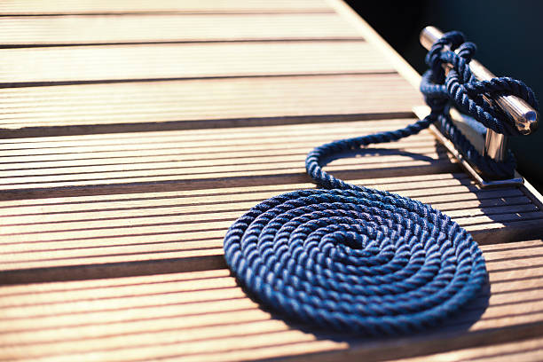 pier cleat and a mooring rope steel pier cleat and a blue mooring rope, shallow DOF cleat stock pictures, royalty-free photos & images