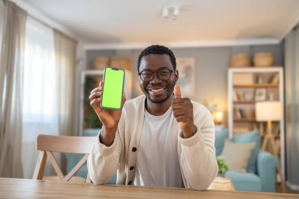istock Black young man shows mobile phone with green screen, Chroma screen 1848384518