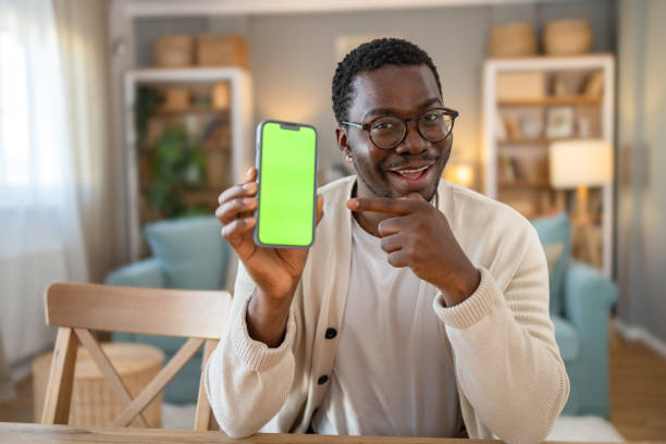 istock Black young man shows mobile phone with green screen, Chroma screen 1848384521