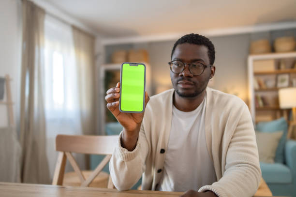 istock Black young man shows mobile phone with green screen, Chroma screen 1848384523