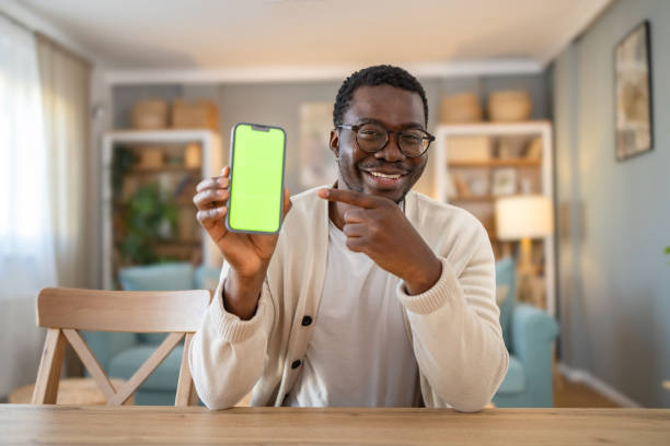 Black young man shows mobile phone with green screen, Chroma screen
