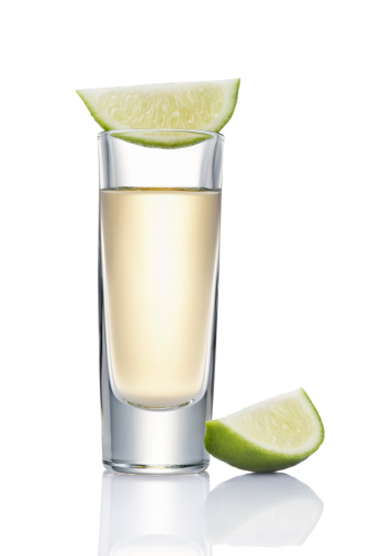 glass of tequila shot with slice of lime beside