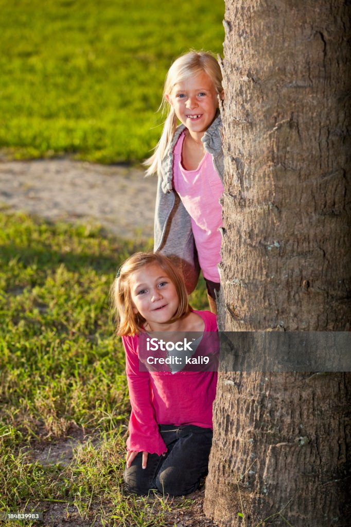 Petites filles jouant derrière arbre - Photo de 4-5 ans libre de droits