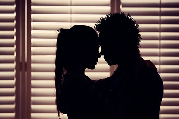Couple In Love Silhouette "Young couple in love share romantic embrace, presented in silhouette and the warm hues of dusk. Horizontal composition." sex and reproduction stock pictures, royalty-free photos & images