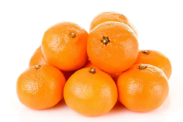 Photo of Pile of bright fresh tangerine fruits on a white background