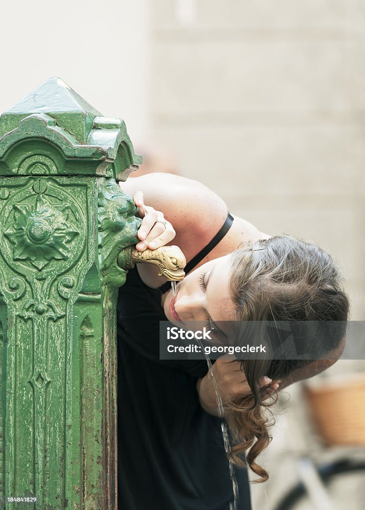 Drinking from a Water Fountain A woman drinking from a water fountain in the town of Como,  in Lombardy, Italy. Adult Stock Photo
