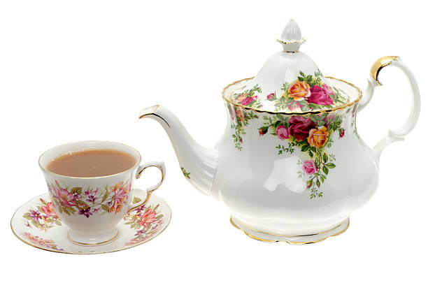 Vintage bone China teapot with a cup of tea. Vintage bone China teapot with a cup of tea - studio shot with a white background english culture photos stock pictures, royalty-free photos & images