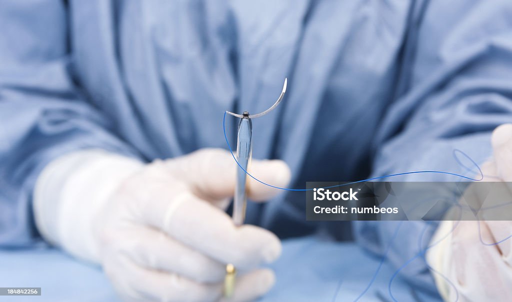 Surgical stitch Doctor holding surgical stitch by scissors during plastic surgery operationMore medical photos; Medical Stitches Stock Photo