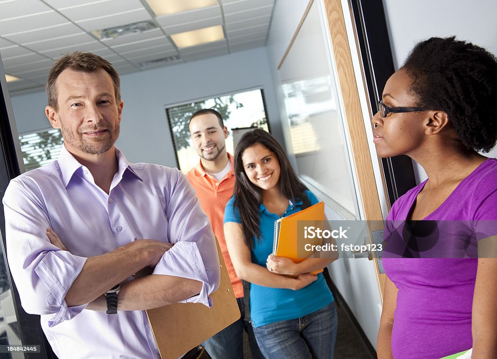 Instructor, professor at door, college students in classroom. Young adult. Instructor at door, students in classroom    Adult Stock Photo