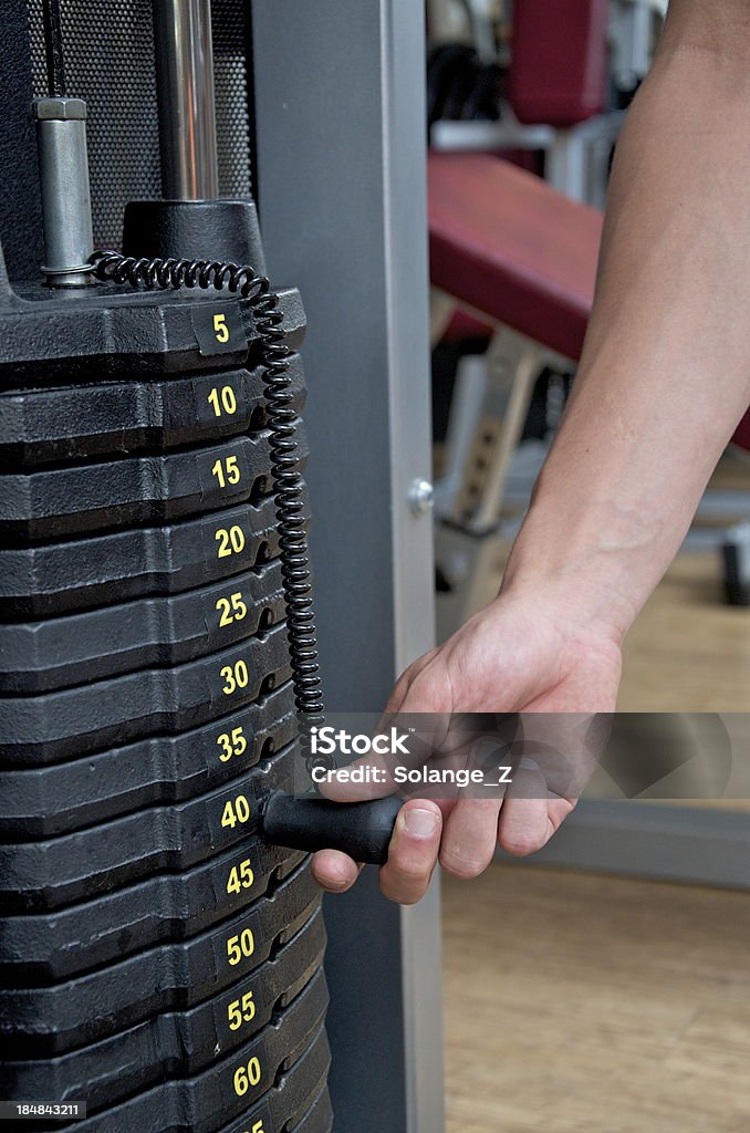 Weigh Lifting A man's hand is setting the weight in a weight lifting machine to exercise. Adult Stock Photo