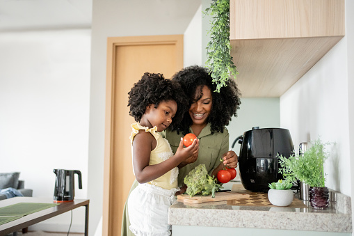 Mother teaching daughter how to prepare vegetables in an oil-free fryer