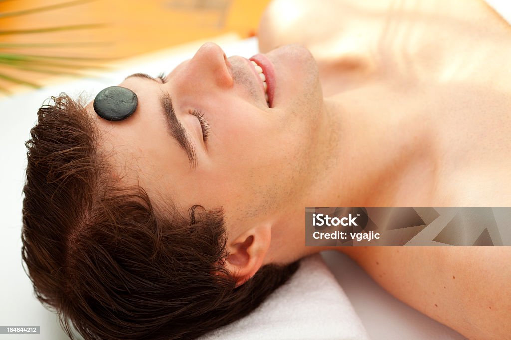 Giovane uomo con Hot Stone Massaggio alla testa nel centro Spa - Foto stock royalty-free di 25-29 anni