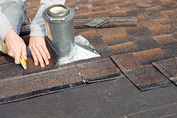istock Roofer Trimming Shingle around Plumbing Vent Flashing 184844234