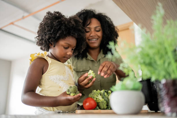 Mother teaching daughter how to prepare vegetables Mother teaching daughter how to prepare vegetables in an oil-free fryer black mother and adult daughter stock pictures, royalty-free photos & images