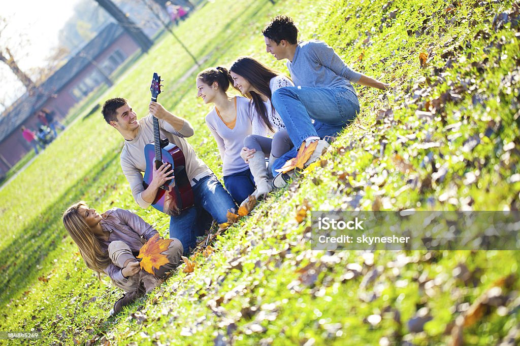 Grupo Médio de Pessoas relaxando no parque com guitarra. - Foto de stock de Adolescente royalty-free