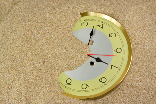 Clock buried in sand. Lost time concept.