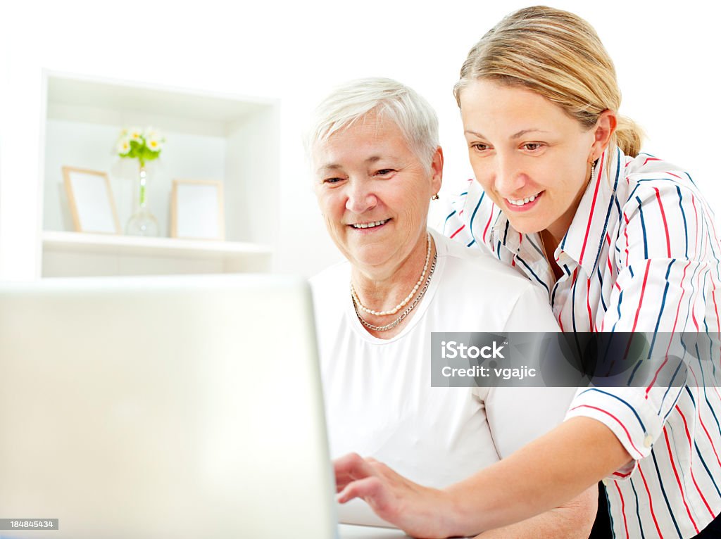 Senior Mujer divirtiéndose en la computadora portátil con su hija adulta - Foto de stock de 35-39 años libre de derechos