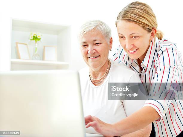 Senior Mujer Divirtiéndose En La Computadora Portátil Con Su Hija Adulta Foto de stock y más banco de imágenes de 35-39 años