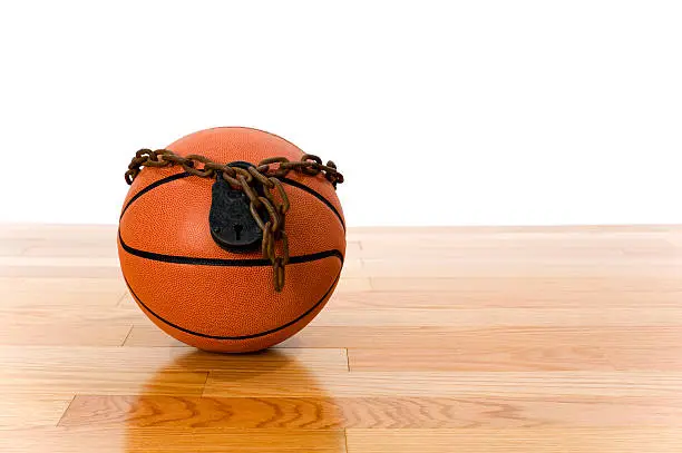 Concept-NBA Lockout. Basketball sitting on hardwood court with a chain and padlock