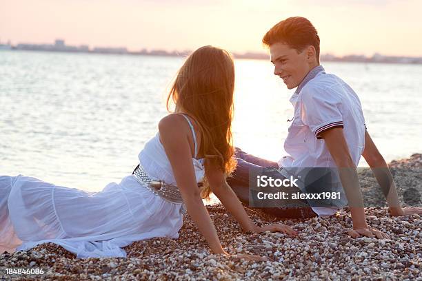 Szczęśliwy Nastoletnie Para Siedzi Razem Na Morze Pebble Beach - zdjęcia stockowe i więcej obrazów Para nastolatków