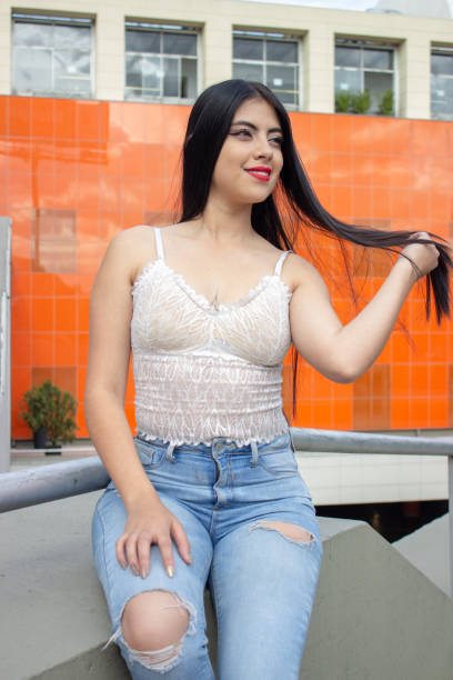 istock beautiful young woman sitting in a wall and modeling 1848462458
