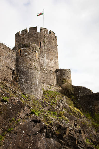 Conwy Castle Tower One of the guard towers of the Conwy Castle atop a steep cliff with the Welsh flag floating above. conwy castle stock pictures, royalty-free photos & images