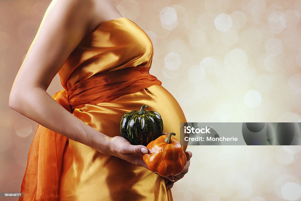 Donna incinta holding pumpkins - Foto stock royalty-free di Addome