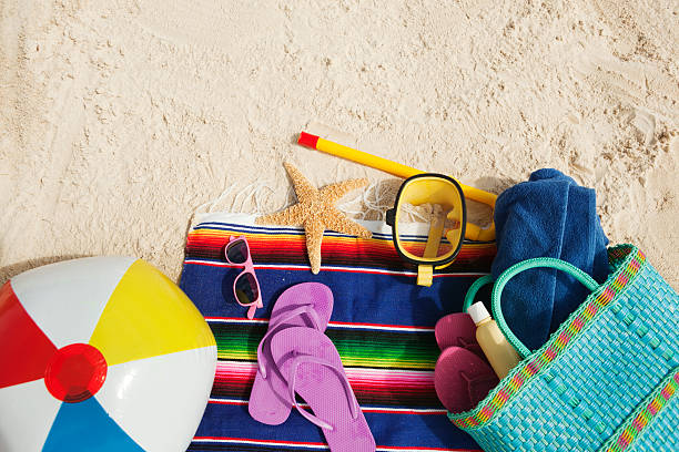Summer Holiday Vacation Beach Bag and Fun Supply and Toy Subject: Various beach gear resting on the sandy beach with copy space. beach bag stock pictures, royalty-free photos & images
