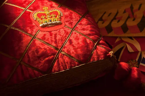 "A still life of Royal ephemera, with a regal cushion bearing the Queens Crown caught in a shaft of light. Queen Elizabeth II is the Queen of the United Kingdom and 15 sovereign states around the world that are known as the Commonwealth. When her father, George VI, died in 1952 she became Queen, although her Coronation did not take place until 1953. In 2012 she had reigned for 60 years, her Diamond Jubilee and her Coronation anniversary will be in June 2013"