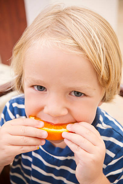 istock Little boy eating an orange 184850212